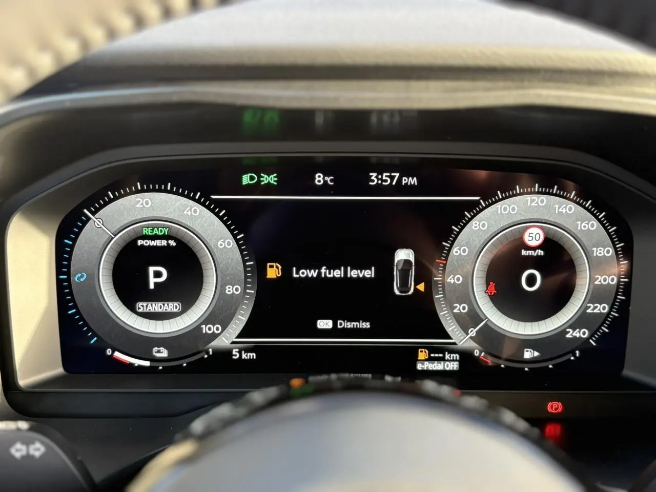 Vue rapprochée du combiné d'instrumentation numérique du Nissan Qashqai noir, affichant un avertissement de faible carburant.