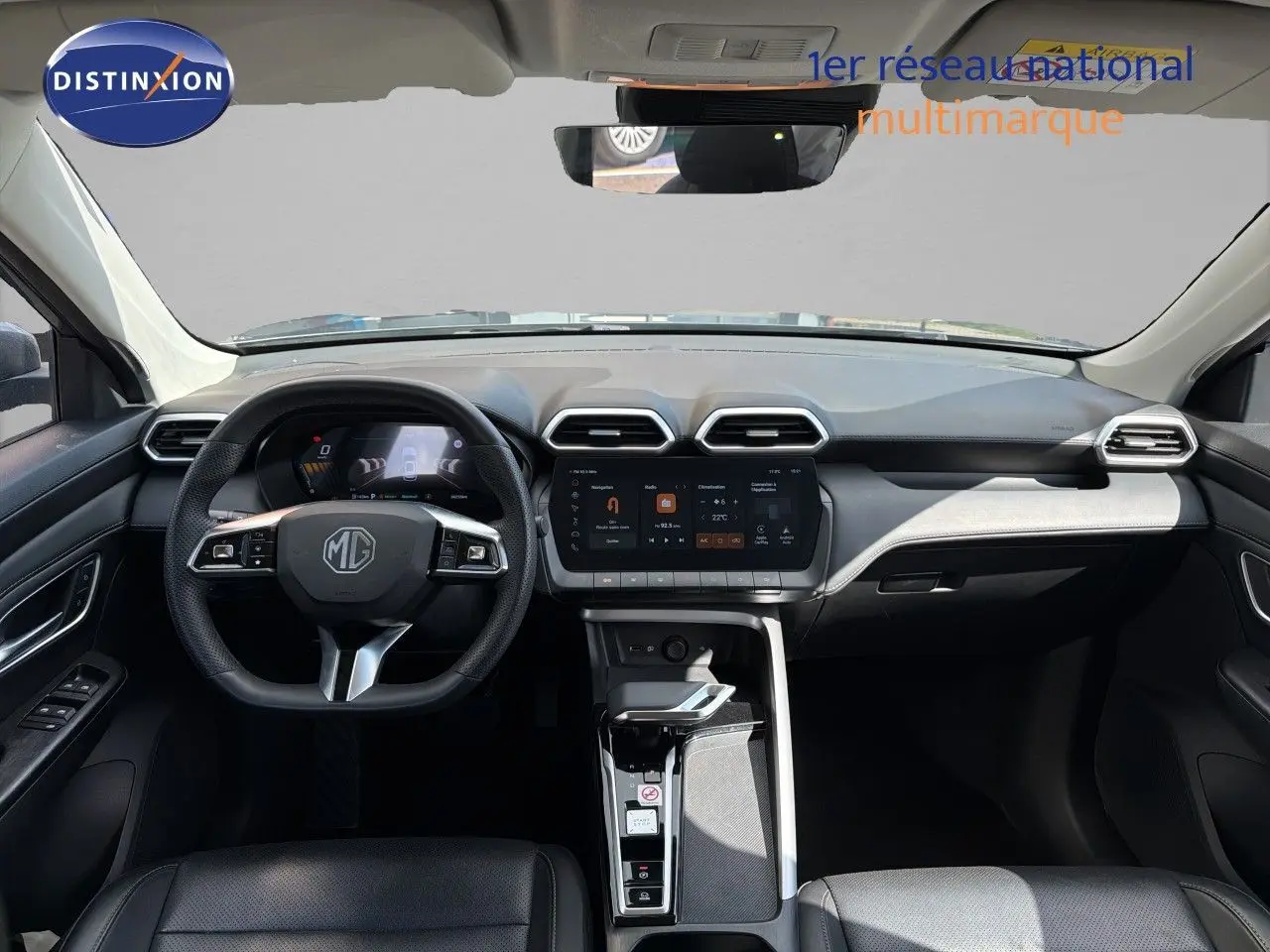Vue intérieure frontale du tableau de bord du MG MOTOR ZS 2025 en gris, avec écran tactile central et volant multifonction cuir.