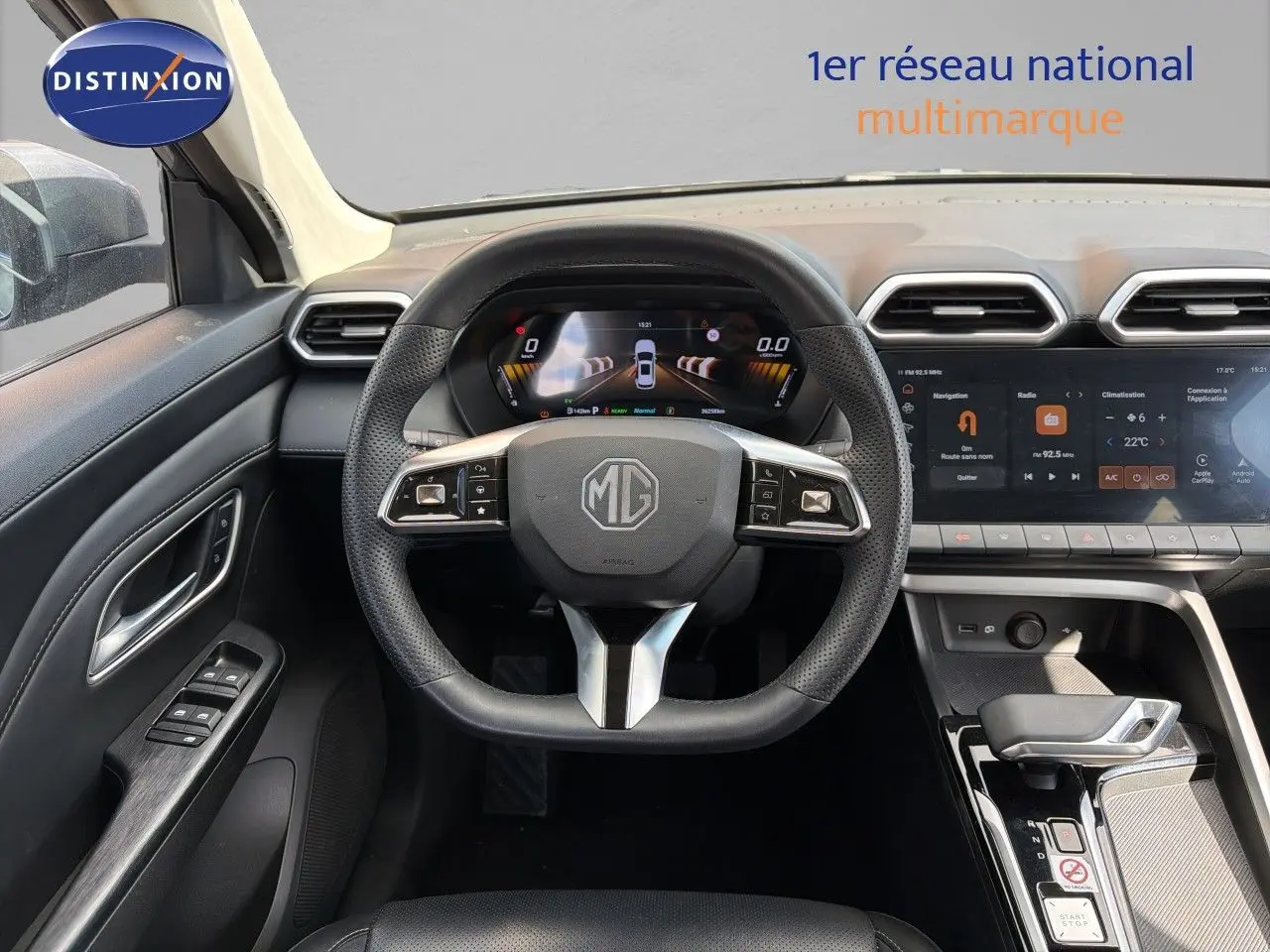 Vue intérieure centrée sur le volant MG d’un MG ZS 1.5L Hybrid+ gris Hampstead avec tableau de bord numérique et écran tactile.
