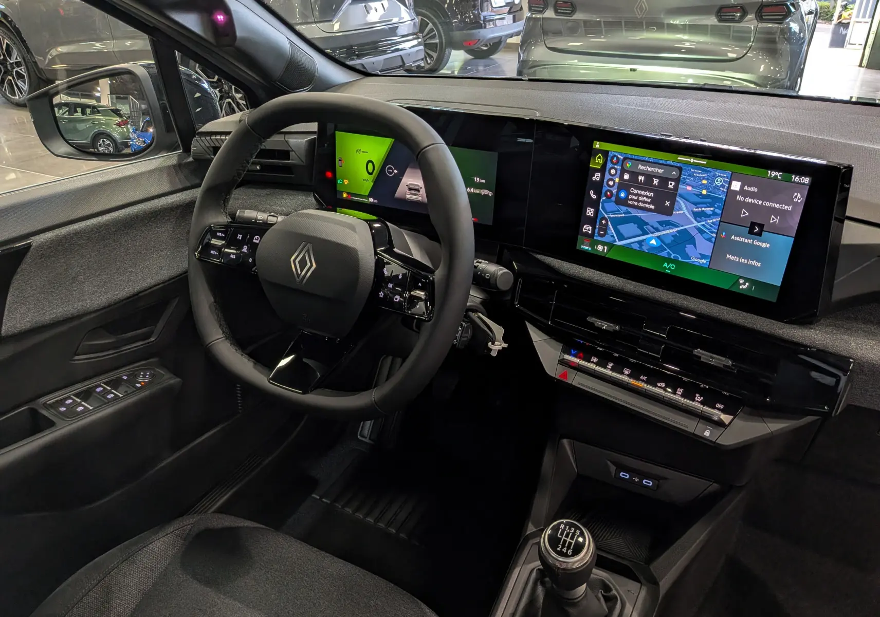 Vue intérieure côté conducteur de la Renault Clio VI gris Rafale, avec tableau de bord numérique et boîte manuelle.