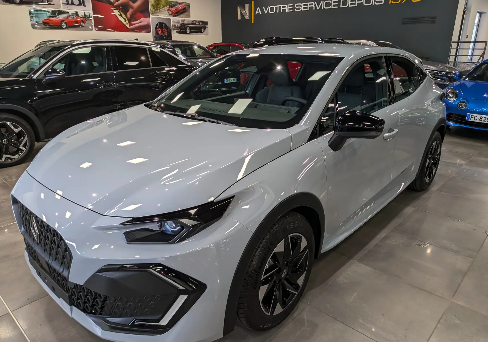 Renault Clio VI gris Rafale vue 3/4 avant droit en intérieur, avec jantes biton et détails noirs contrastants.