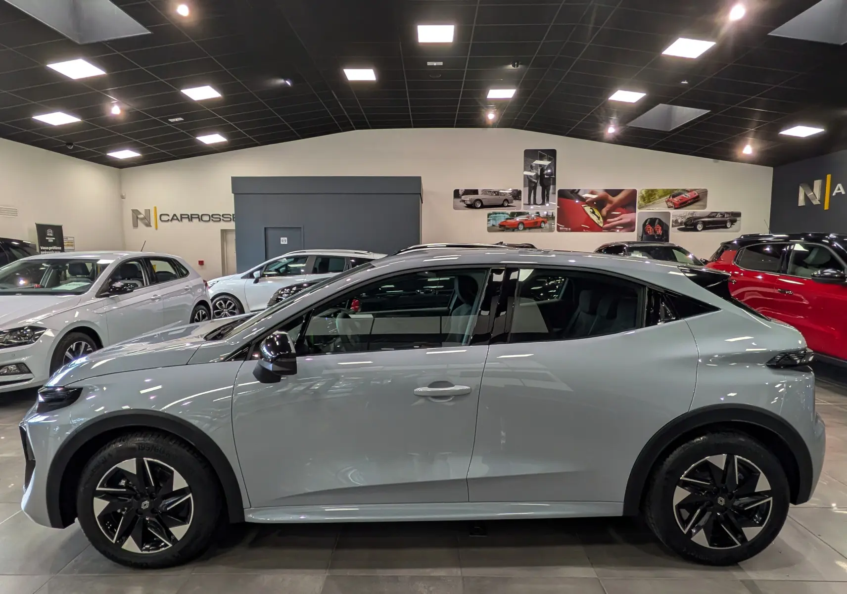 Profil côté gauche de la Renault Clio VI gris Rafale 2026 en showroom, soulignant ses jantes biton et lignes modernes.