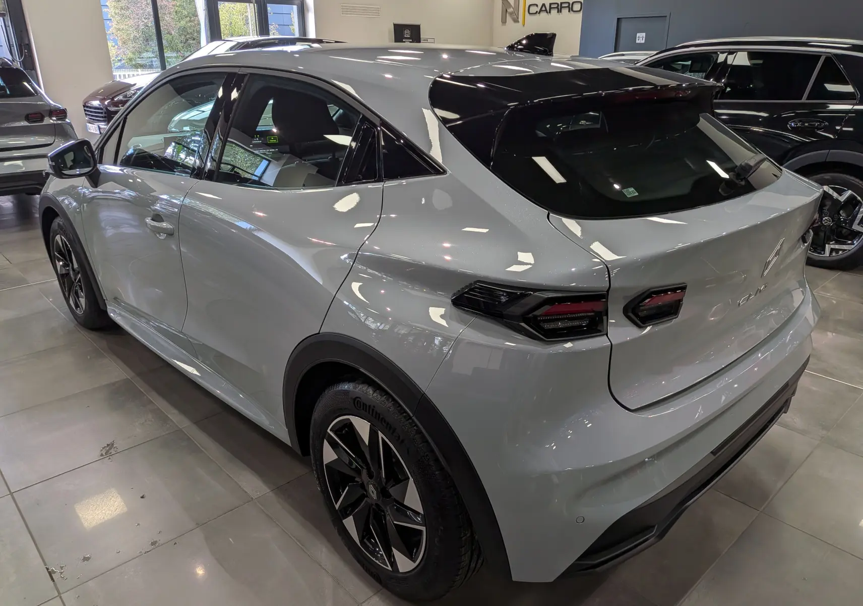 Vue 3/4 arrière droite de la Renault Clio VI gris Rafale, avec jantes bi-ton et feux arrière LED distinctifs.