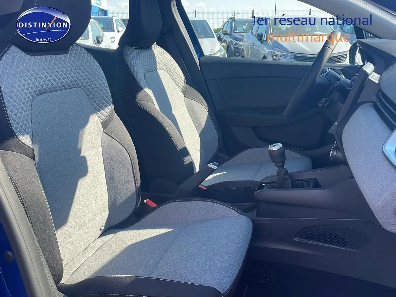 Intérieur avant droit de Renault Clio V bleu iron 2025, sièges tissu bicolore et boîte manuelle visible