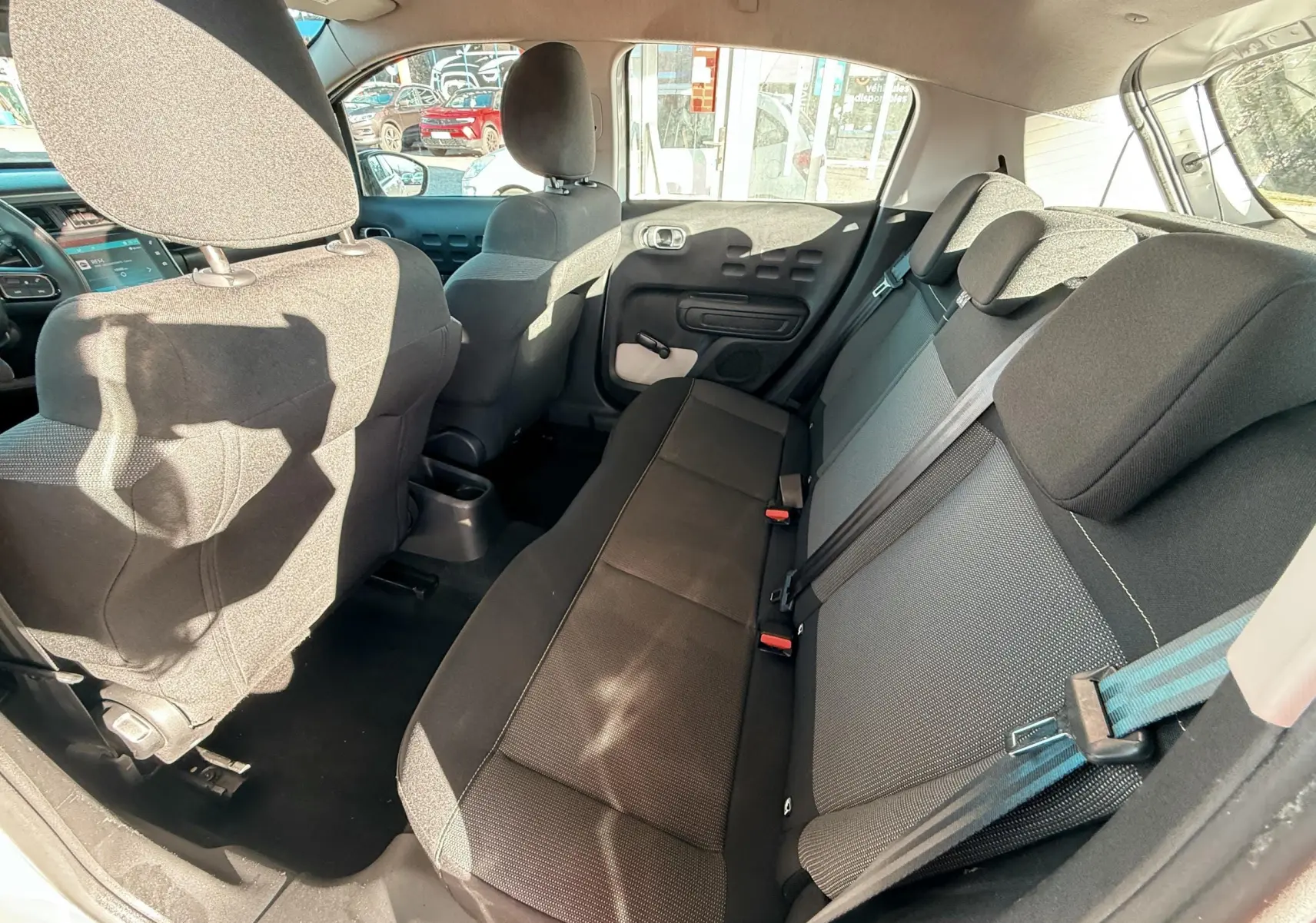 Vue intérieure arrière côté droit montrant les sièges tissu gris et noir d'une Citroën C3 blanche 2017.