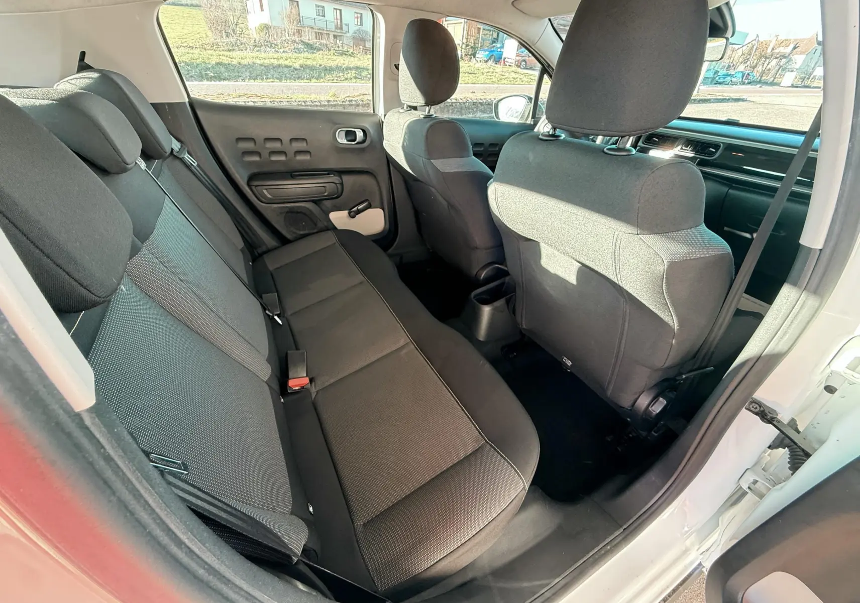 Vue intérieure arrière côté droit d'une Citroën C3 blanche de 2017, sièges tissu gris foncé et noir.