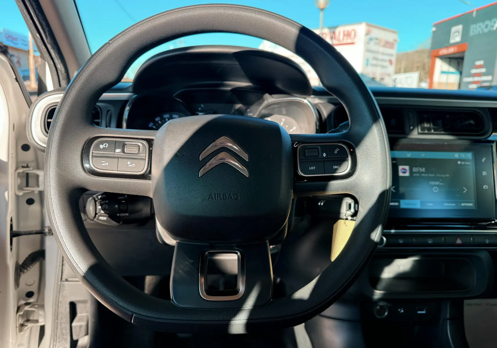 Vue centrée sur le volant Citroën C3 blanc, avec tableau de bord et écran tactile en arrière-plan.