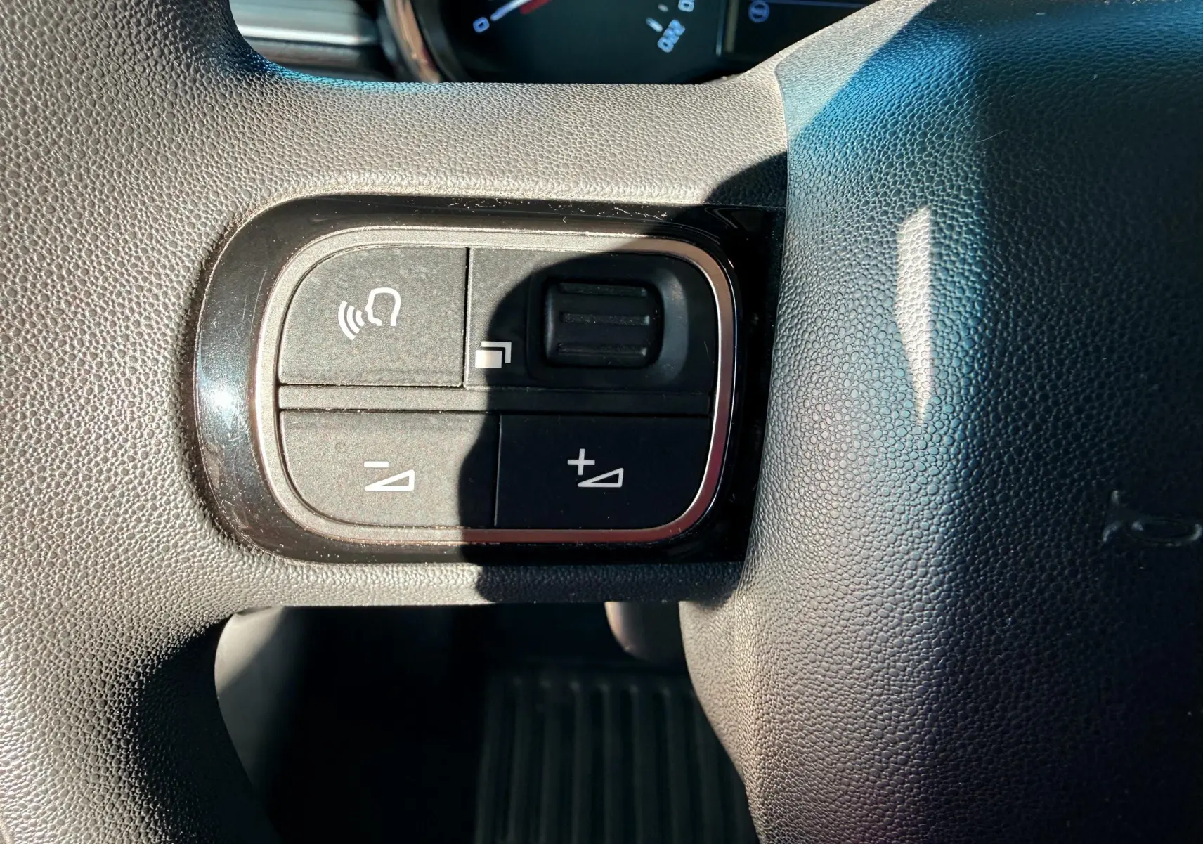 Gros plan sur les commandes de volume et téléphone au volant noir de la Citroën C3 2017.