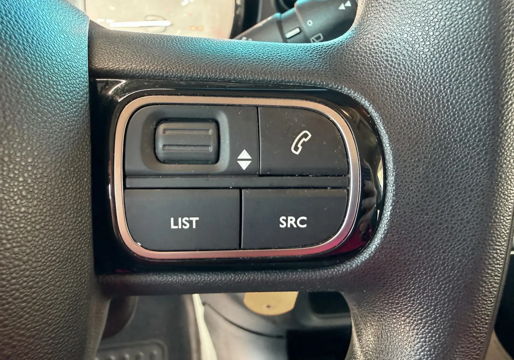 Gros plan sur les boutons de commande audio et téléphone sur le volant noir d'une Citroën C3 2017.