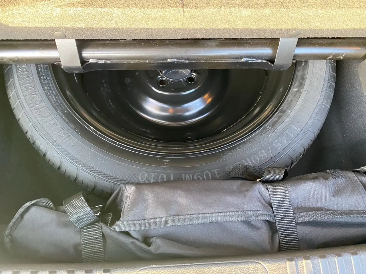 Gros plan sur la roue de secours et le rangement sous le coffre du Renault Espace blanc nacré 2025.