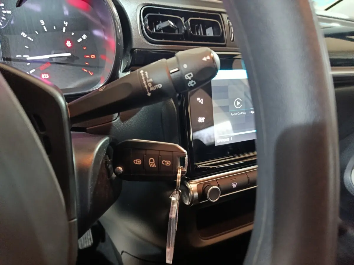 Vue rapprochée de l'intérieur côté conducteur de la Citroën C3 gris clair, avec clé insérée et écran tactile central allumé.