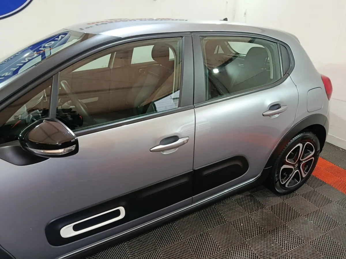 Vue latérale droite d'une Citroën C3 gris clair avec protections de porte noires et jantes stylisées.