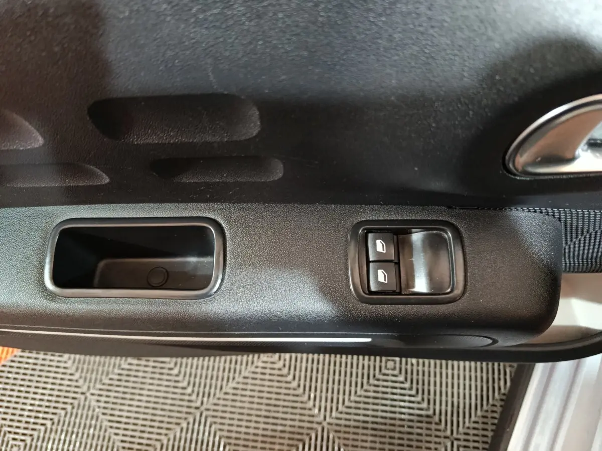 Vue rapprochée de la porte côté conducteur d'une Citroën C3 gris clair, avec commandes électriques des vitres.