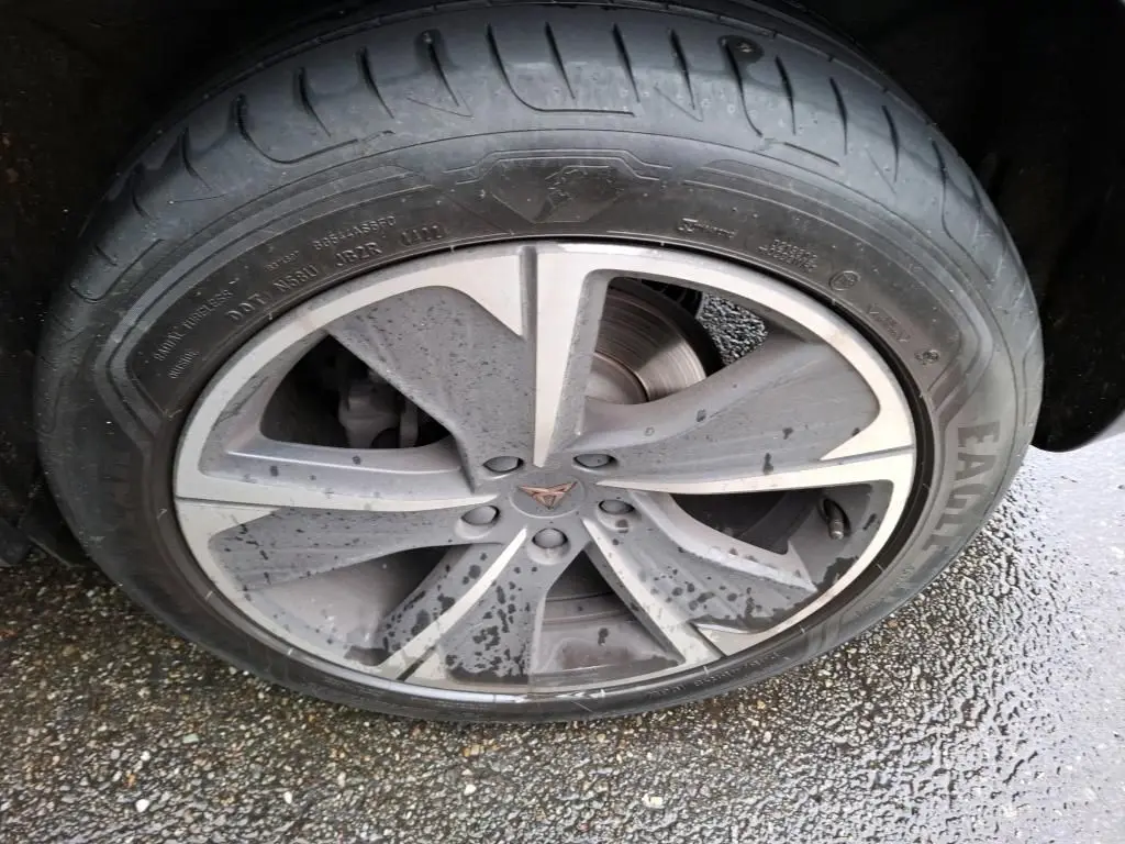 Gros plan sur la jante alu grise avec logo CUPRA au centre, roue arrière d'un CUPRA Formentor noir sous la pluie.