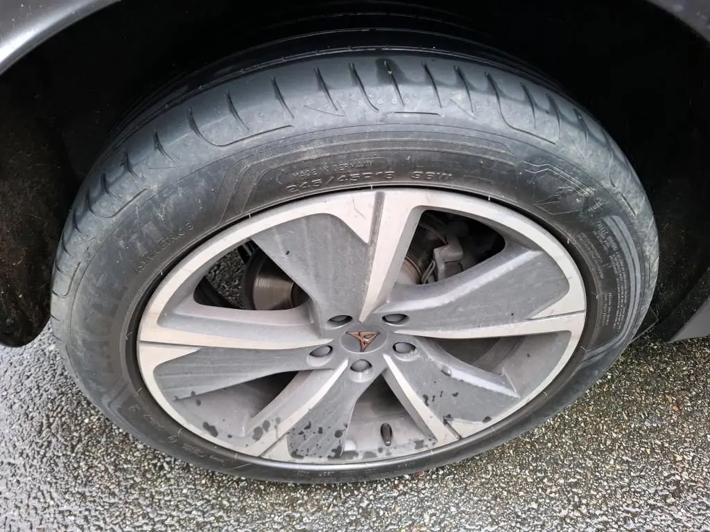 Gros plan sur la jante alu grise avec logo CUPRA au centre, sur le côté droit d'une CUPRA Formentor noire.