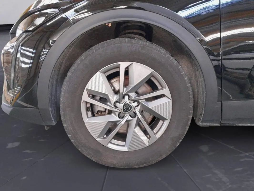 Gros plan sur la roue avant gauche d’une Peugeot 408 PHEV 180 e-EAT8 Allure noire avec jante alliage 17 pouces.