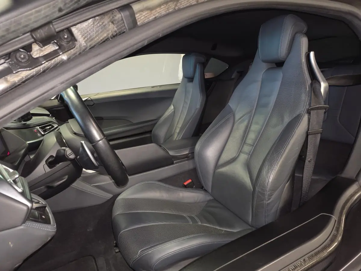 Vue intérieure côté conducteur de la BMW i8 Coupé Pure Impulse 2015 avec sièges sport en cuir gris et détails carbone.