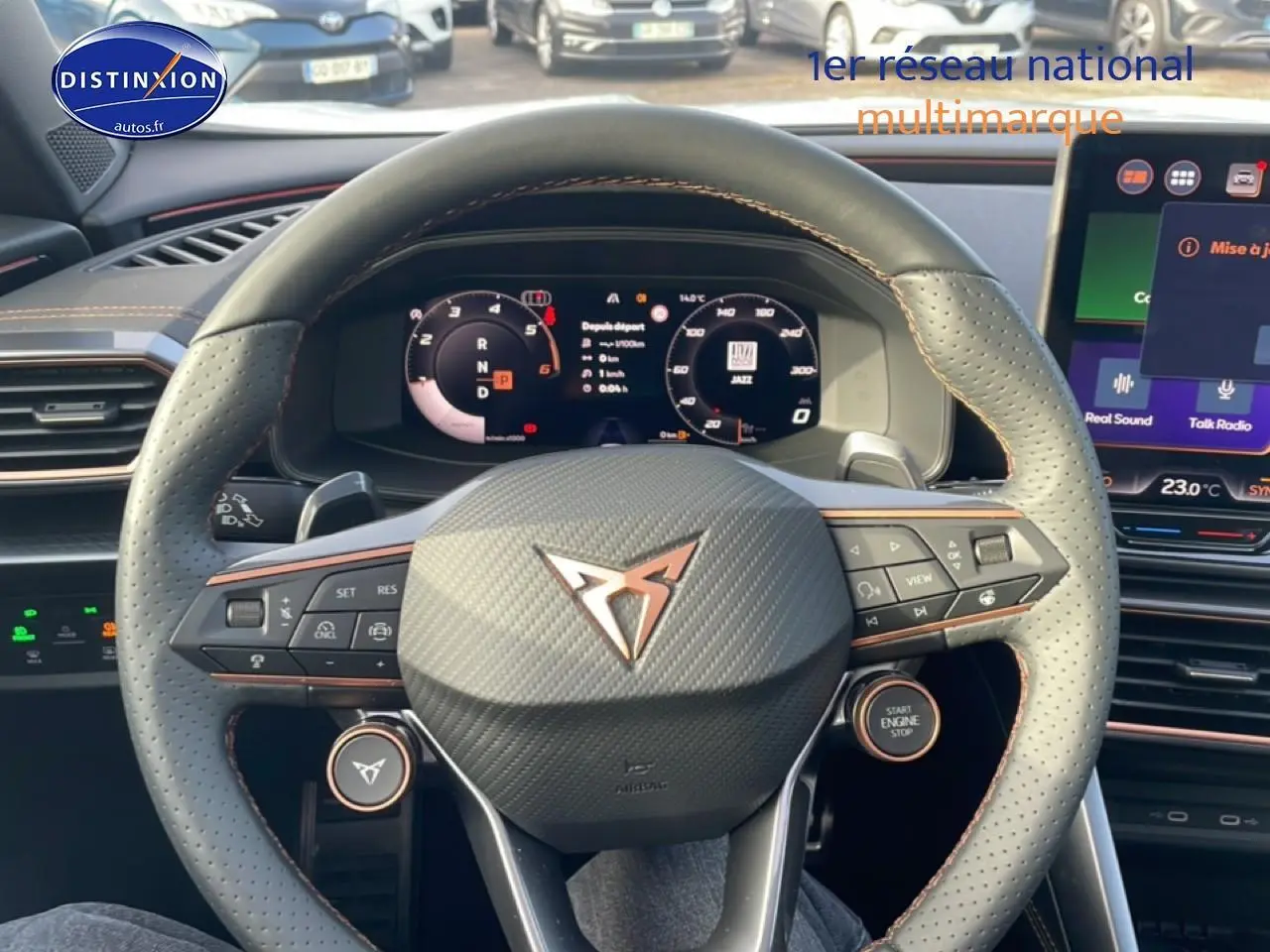 Vue intérieure centrée sur le volant cuir perforé gris avec logo CUPRA et tableau de bord numérique lumineux.