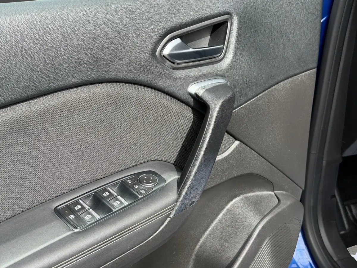 Gros plan sur la porte intérieure côté conducteur du Renault Symbioz bleu, avec commandes de vitres et poignée noire.
