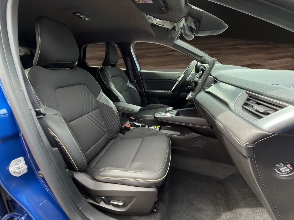 Intérieur avant droit de la Renault SYMBIOZ bleu 2025, sièges noirs avec surpiqûres, tableau de bord moderne et volant multifonctions.