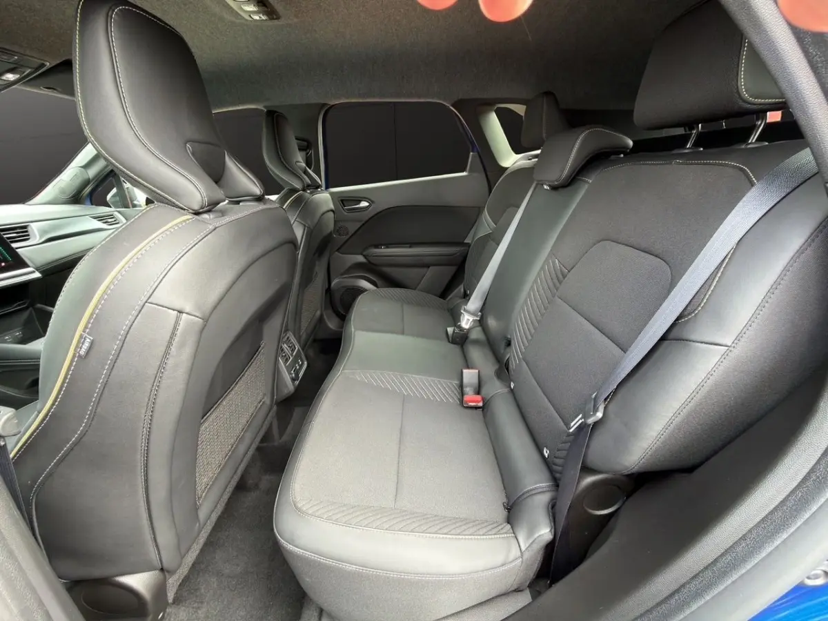 Vue intérieure arrière droite des sièges noirs en cuir et tissu du Renault Symbioz bleu, avec ceinture de sécurité visible.