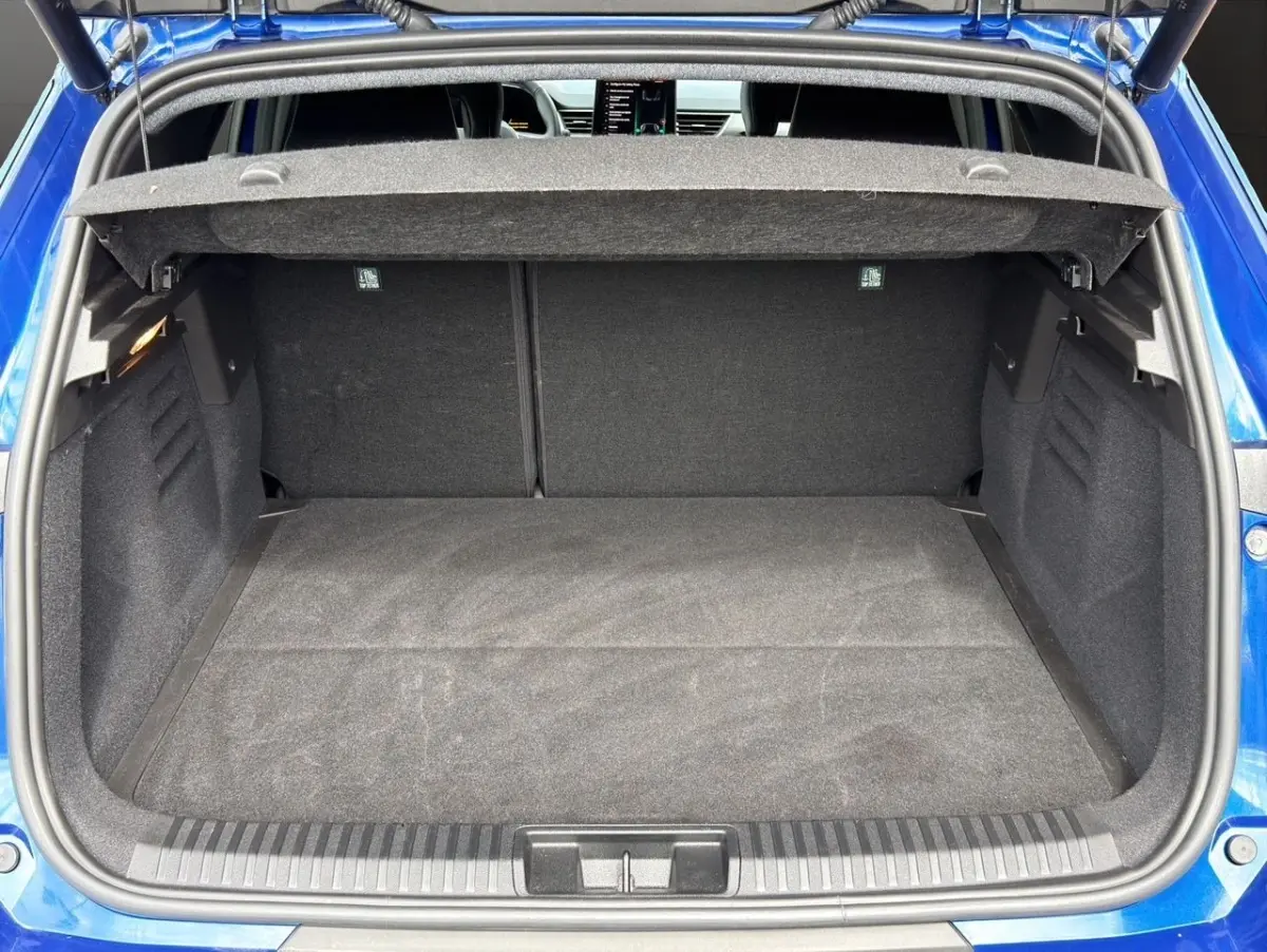 Vue arrière du coffre ouvert d'une Renault SYMBIOZ bleu, montrant l'espace de chargement et la tablette arrière.