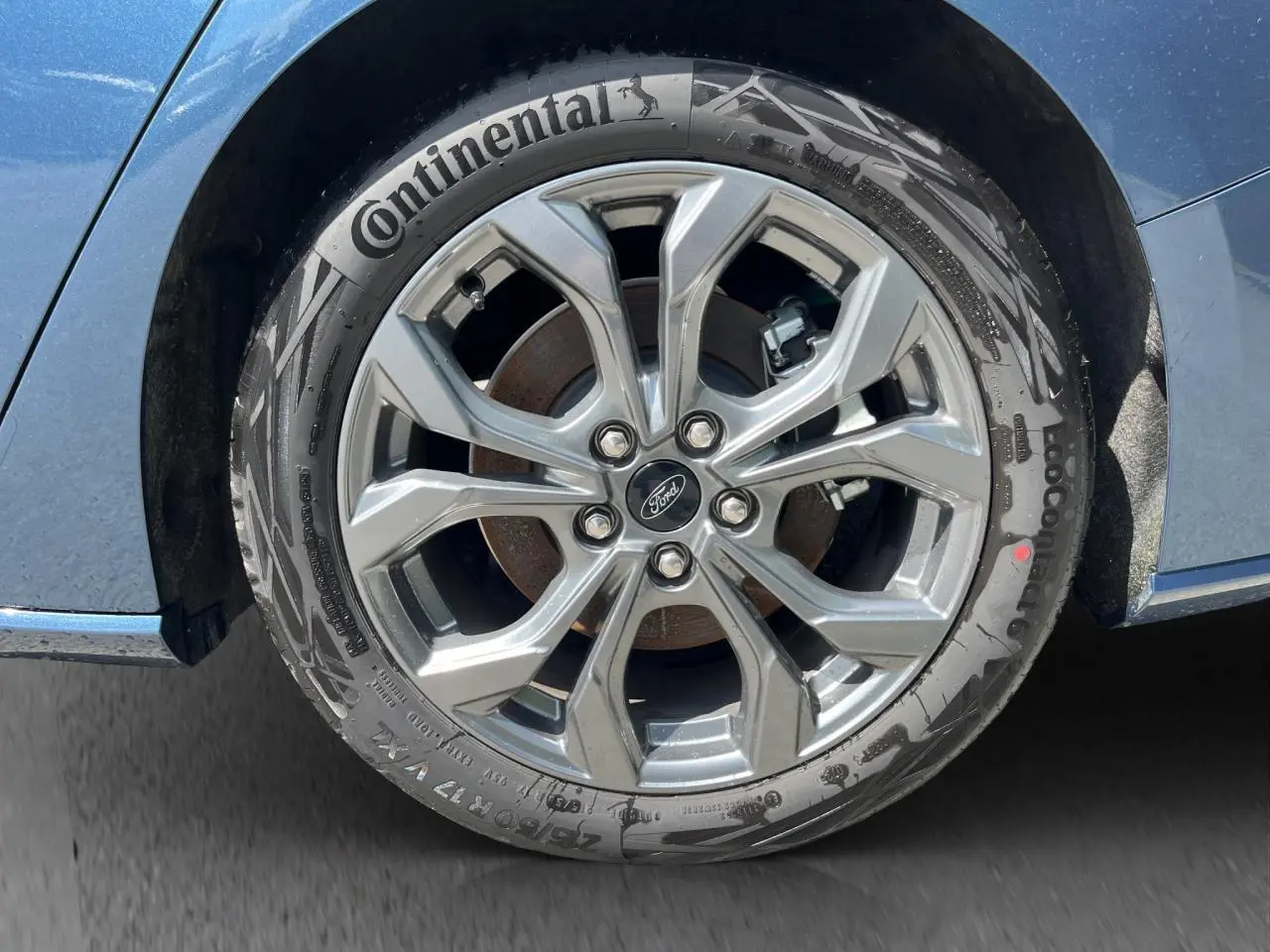 Gros plan sur la roue avant droite d’une Ford Focus SW bleue 2025 avec jante alliage et pneu Continental.