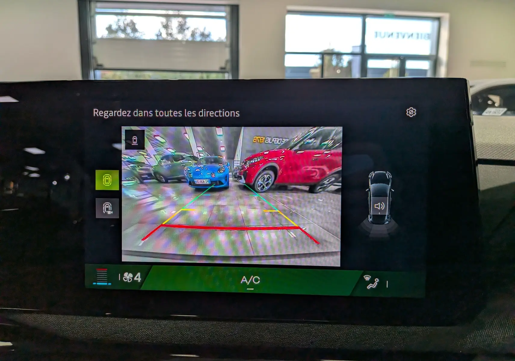 Écran de caméra de recul montrant un parking avec une Renault Clio VI gris schiste en intérieur, vue arrière.