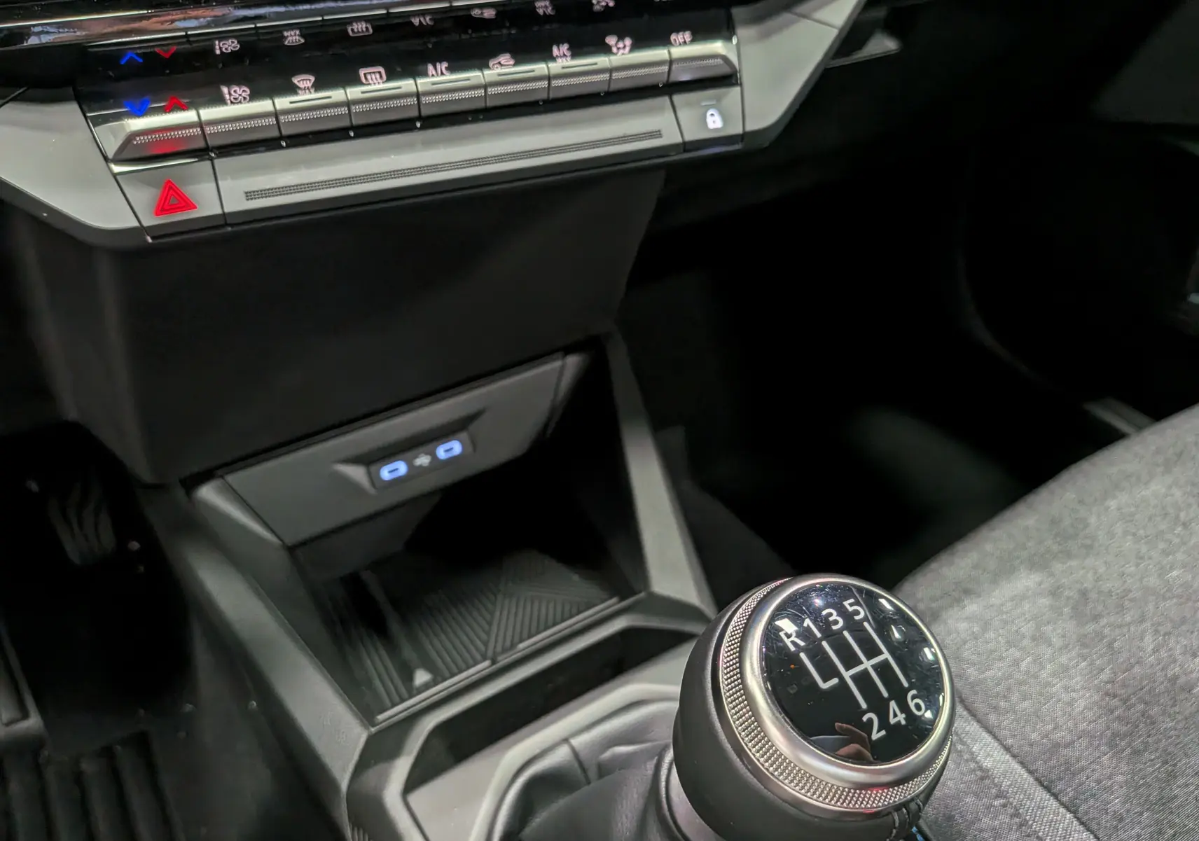 Gros plan sur la console centrale et le levier de vitesse manuel de la Renault Clio VI gris schiste, avec commandes climatisation visibles.