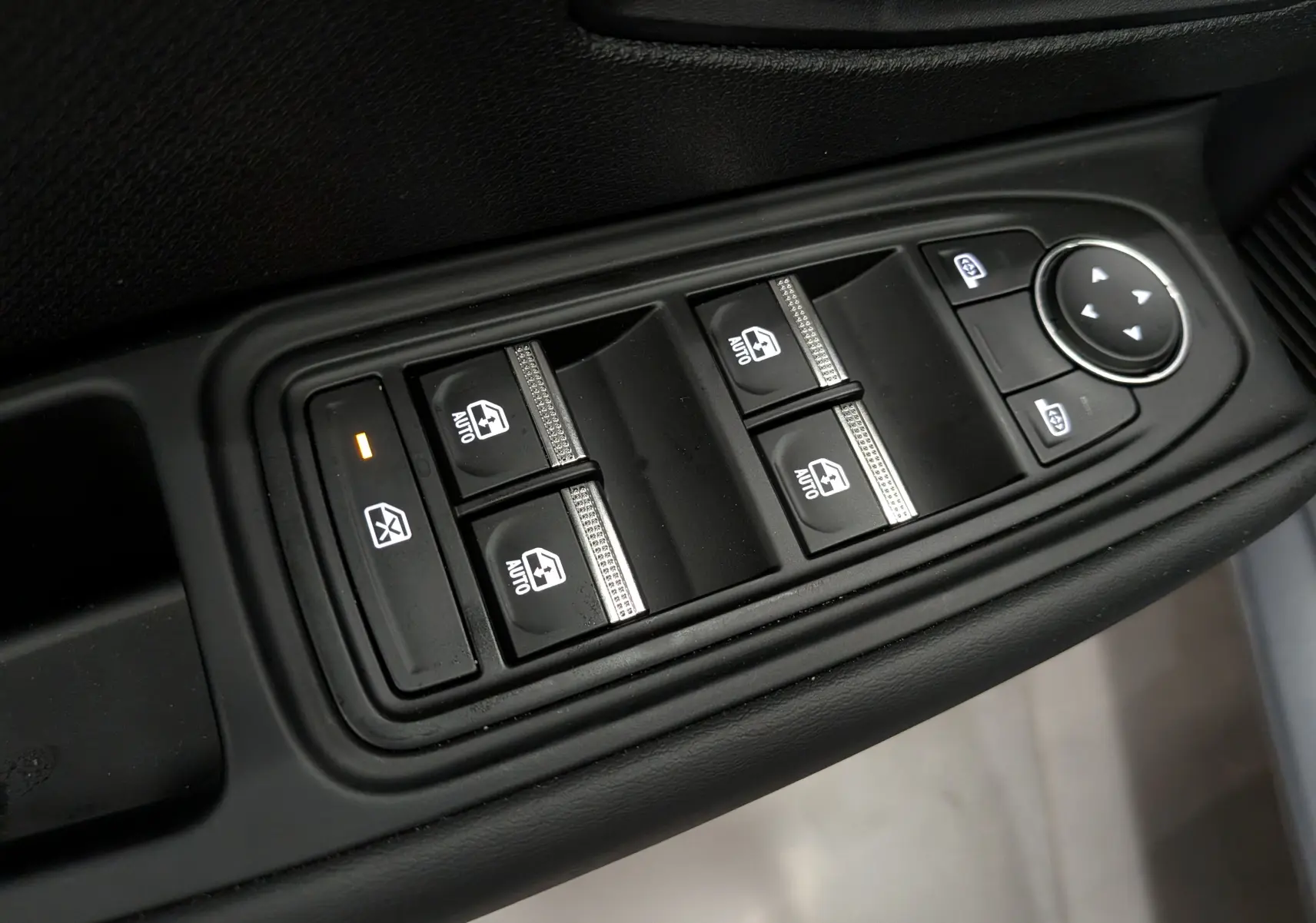 Gros plan sur les commandes de lève-vitres et rétroviseurs électriques noires de la Renault Clio VI Gris Schiste.