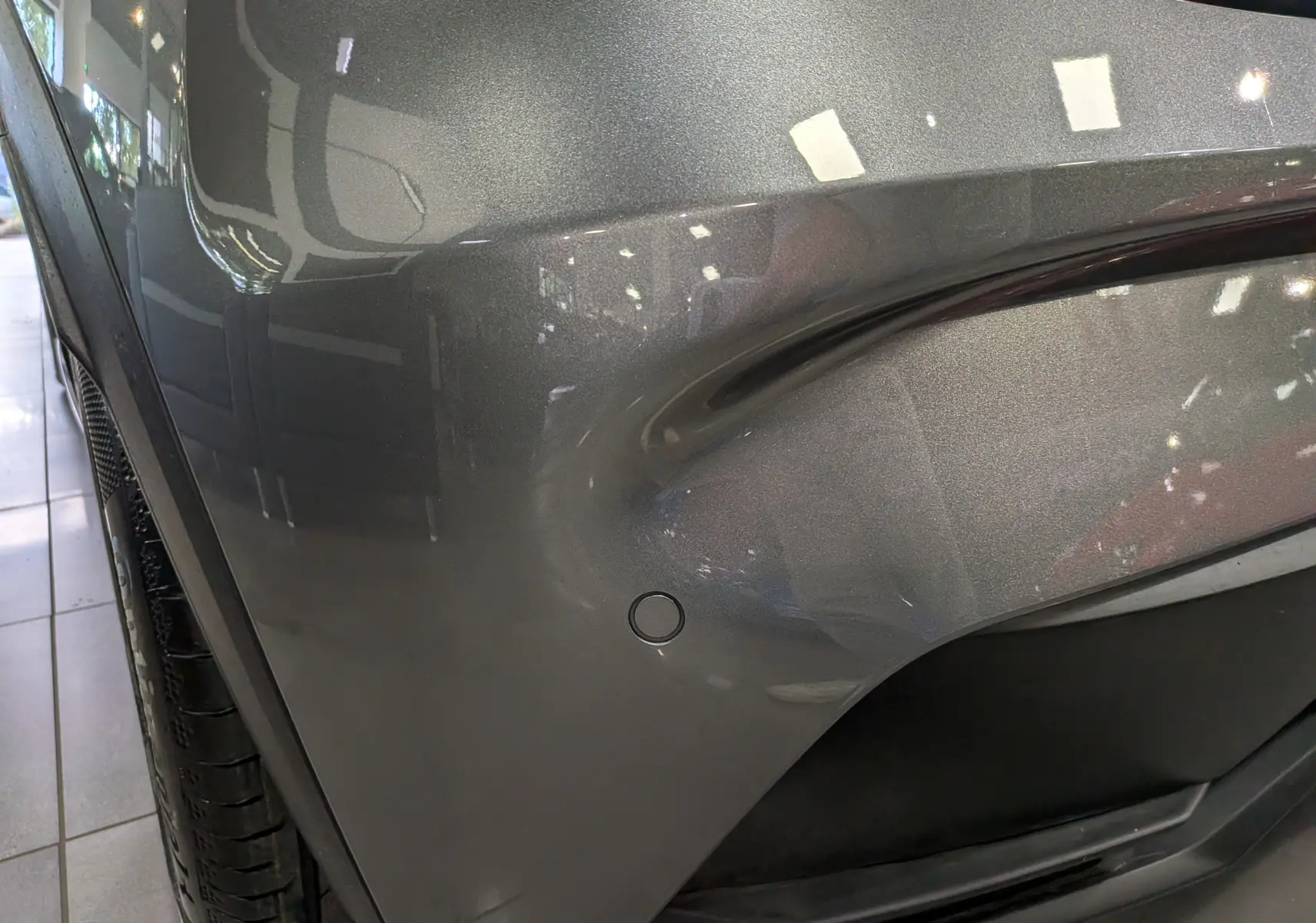 Gros plan sur l’aile avant gauche gris schiste de la Renault Clio VI 1.2 TCe 115 CH Evolution avec capteur de stationnement visible.