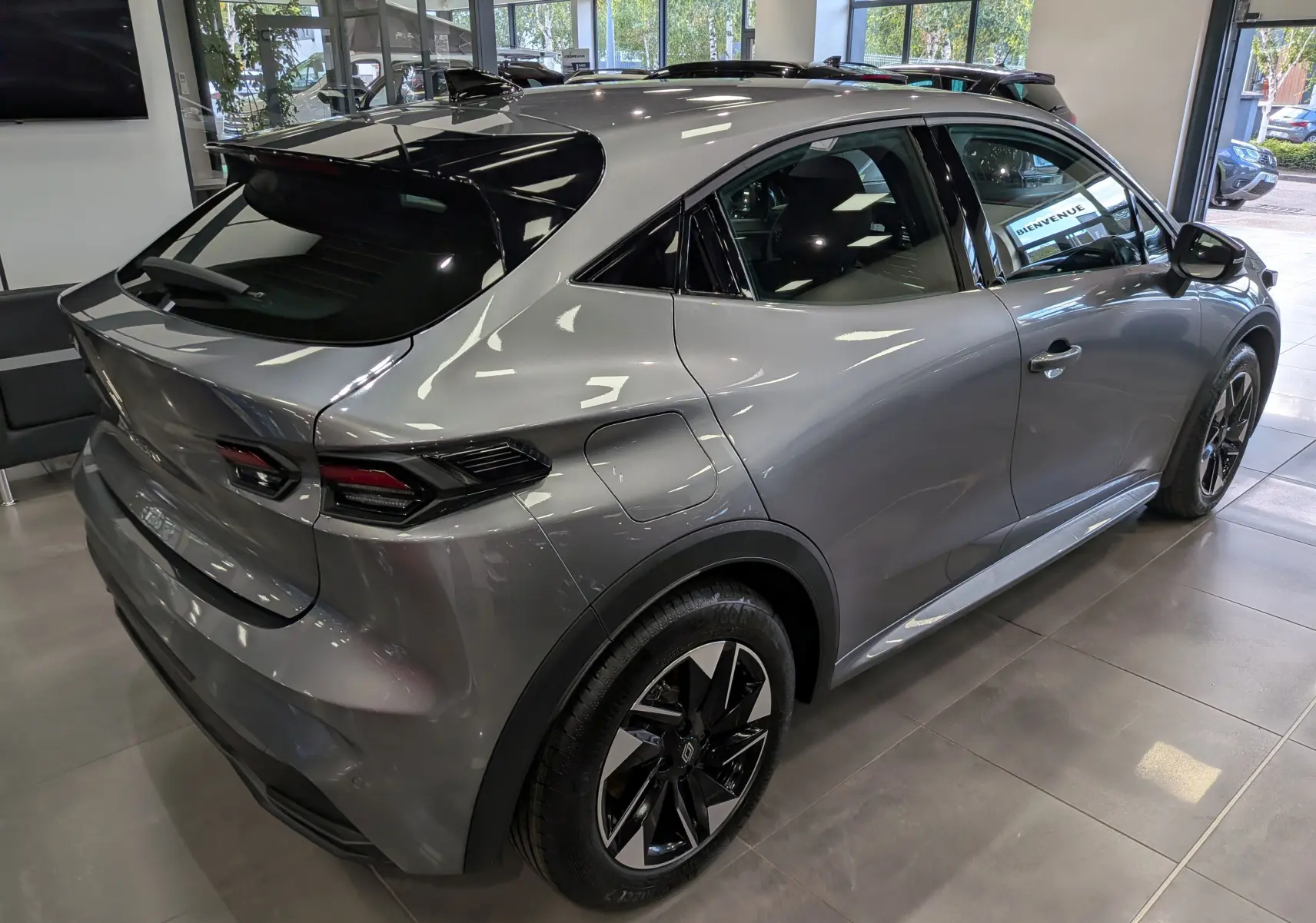 Vue 3/4 arrière droite d'une Renault Clio VI gris schiste avec toit noir et jantes biton en concession.