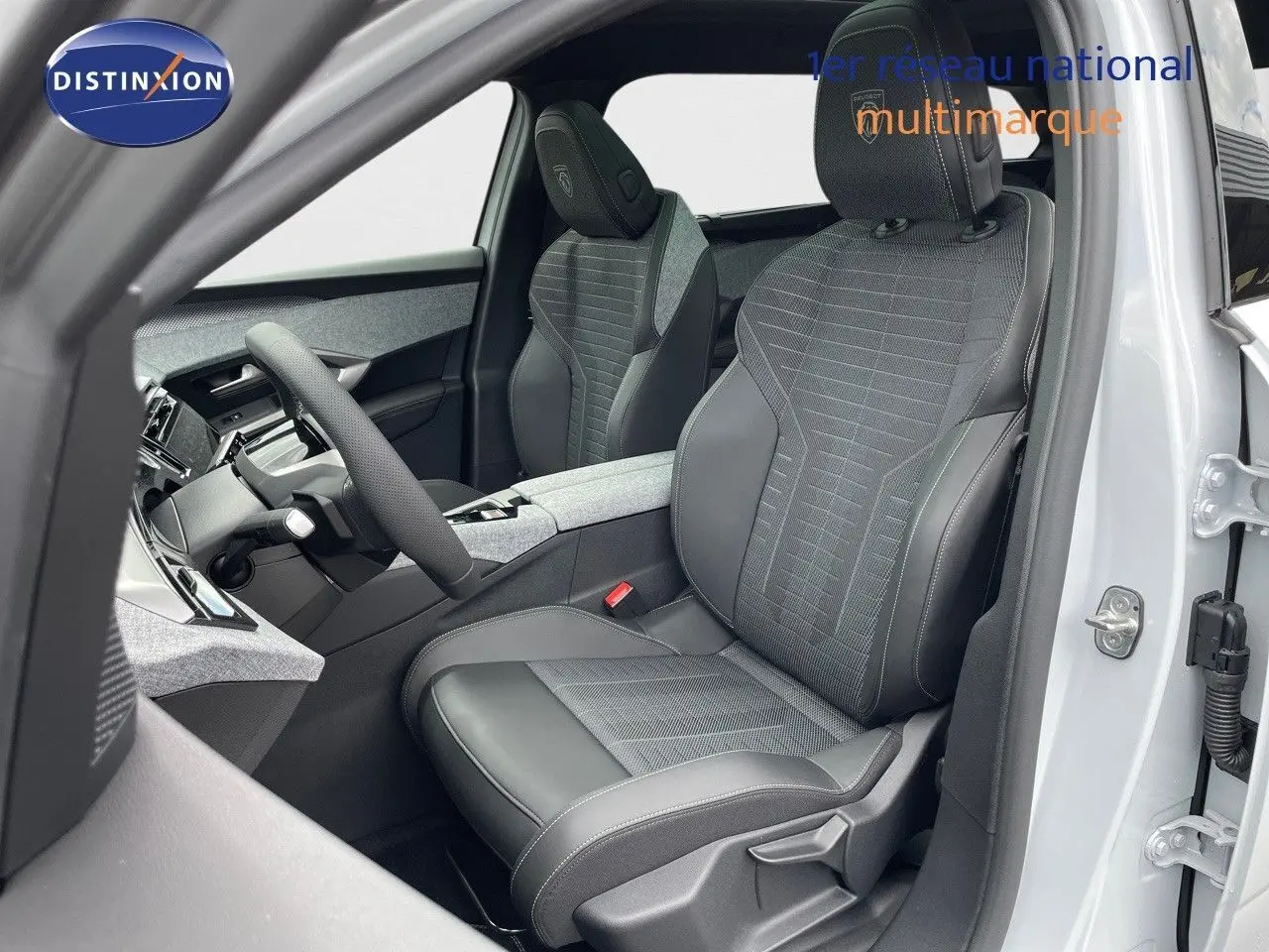 Vue intérieure côté conducteur du Peugeot 5008 Hybrid 2025 avec sièges en cuir noir et tissu gris, tableau de bord moderne.