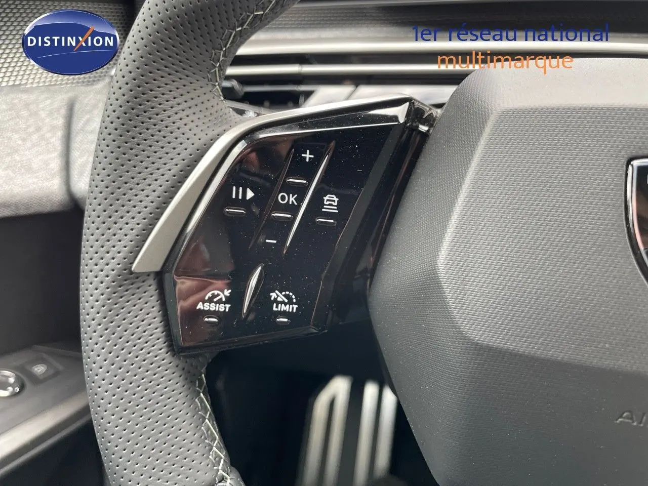 Gros plan sur les commandes à gauche du volant perforé du Peugeot 5008 Hybrid 2025 avec finition noire.