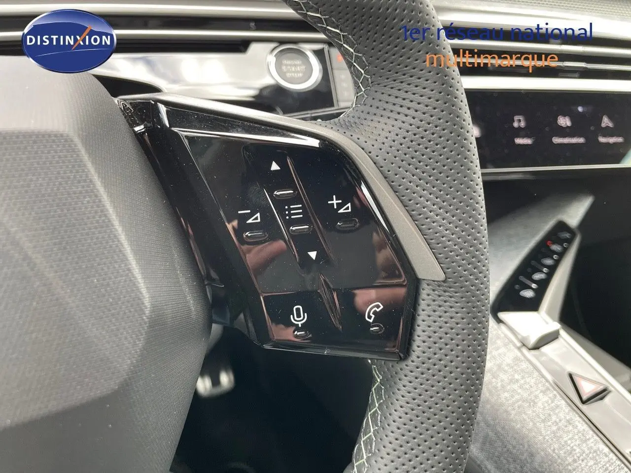 Gros plan sur les commandes tactiles gauche du volant perforé du Peugeot 5008 Hybrid blanc Okenite 2025.
