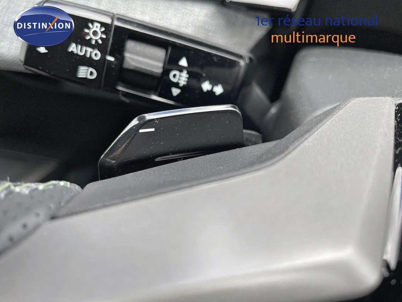 Gros plan sur la commande de feux et le levier de vitesse au volant d'un Peugeot 5008 HYBRID blanc et toit noir.