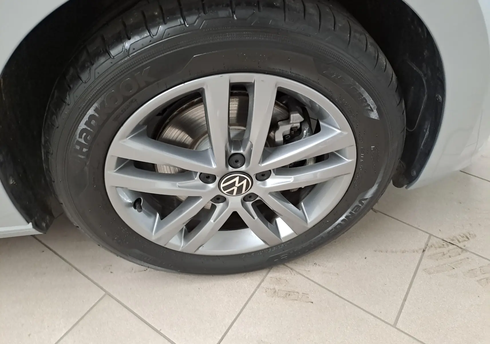 Gros plan sur la roue avant droite argentée avec jante alliage et logo Volkswagen sur un Touran 2025 Argent Dolomite.