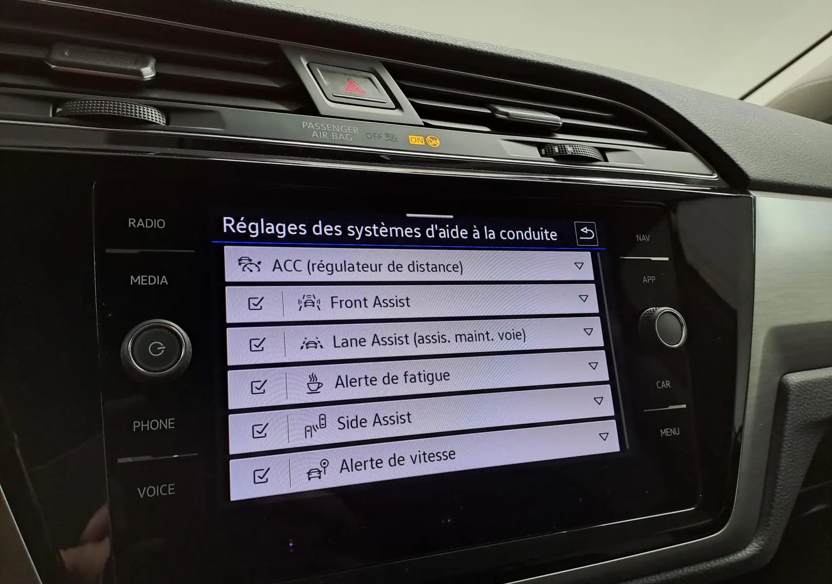 Écran tactile intérieur du Volkswagen Touran 2025 affichant les réglages des aides à la conduite.