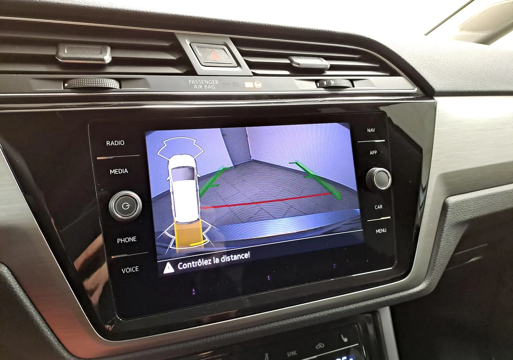 Écran central du Volkswagen Touran 2025 affichant la caméra de recul avec alertes de distance, intérieur gris et noir.