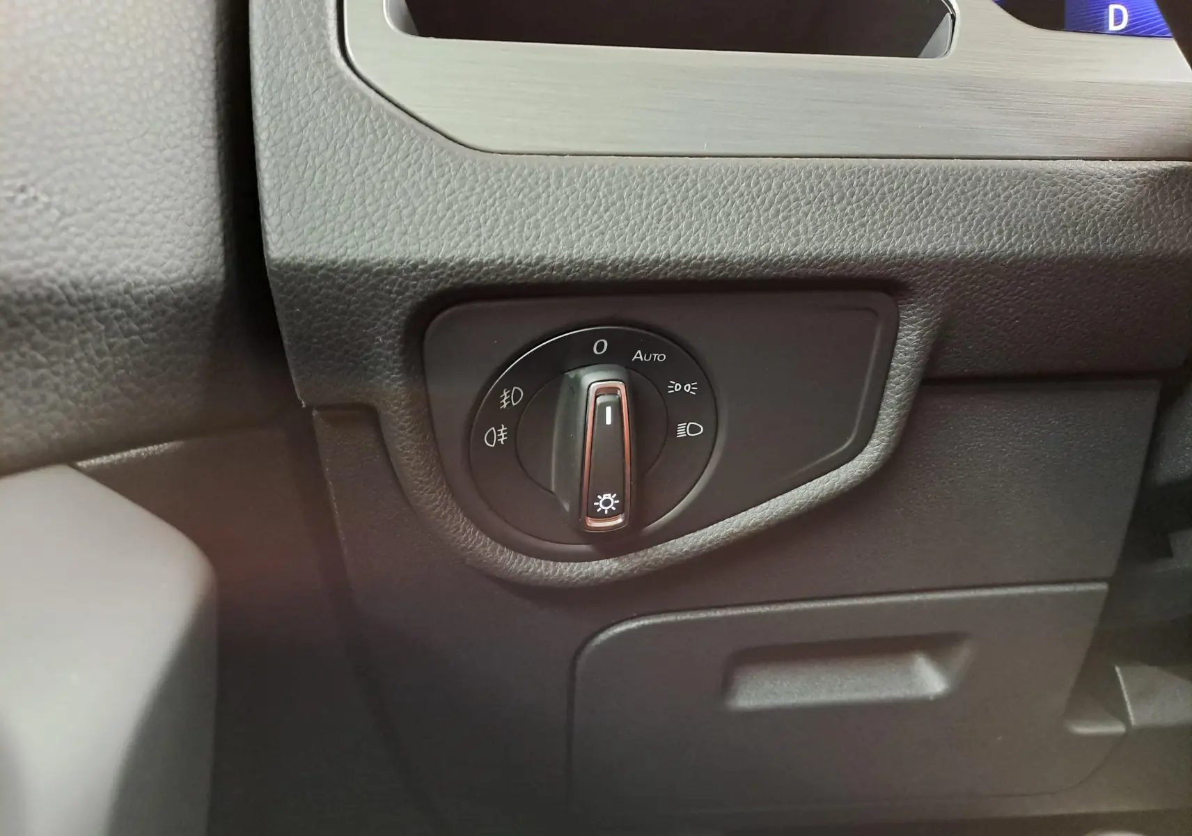 Gros plan sur la molette de commande des phares dans l’habitacle noir du Volkswagen Touran 2025.