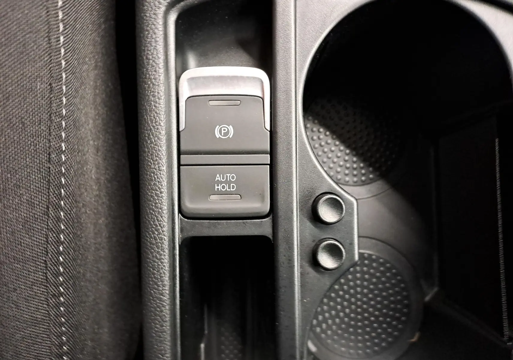 Gros plan sur la console centrale avec frein à main électronique et porte-gobelets du Volkswagen Touran 2025 argent Dolomite.