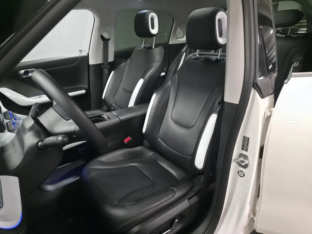 Vue intérieure côté conducteur d'une Smart Electric blanche 2024 avec sièges cuir noirs et inserts blancs.