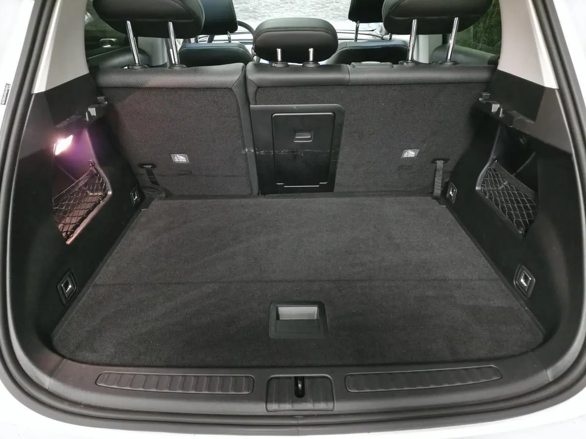 Vue arrière du coffre noir spacieux du Smart #1 Electric Premium blanc 2024 avec banquette arrière et filets latéraux.