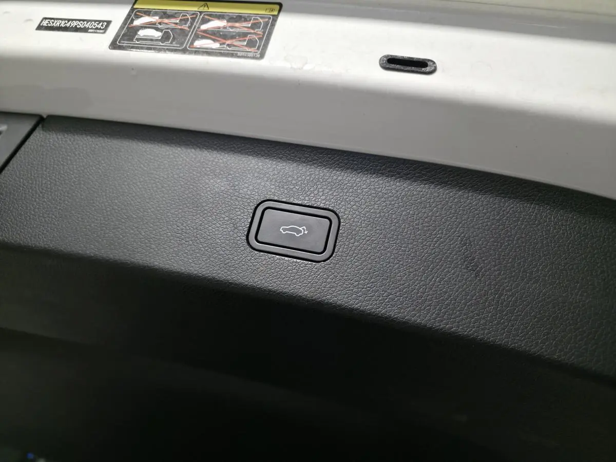 Gros plan sur le bouton d'ouverture électrique du coffre, intérieur noir et blanc du Smart #1 Electric 2024.