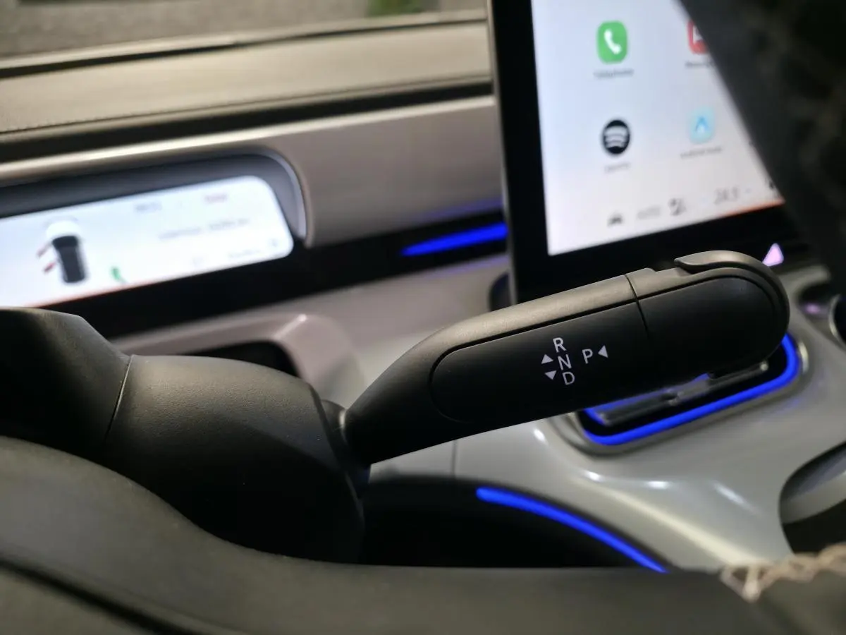 Gros plan sur la commande de boîte automatique noire dans l’habitacle lumineux du Smart Electric blanc 2024.