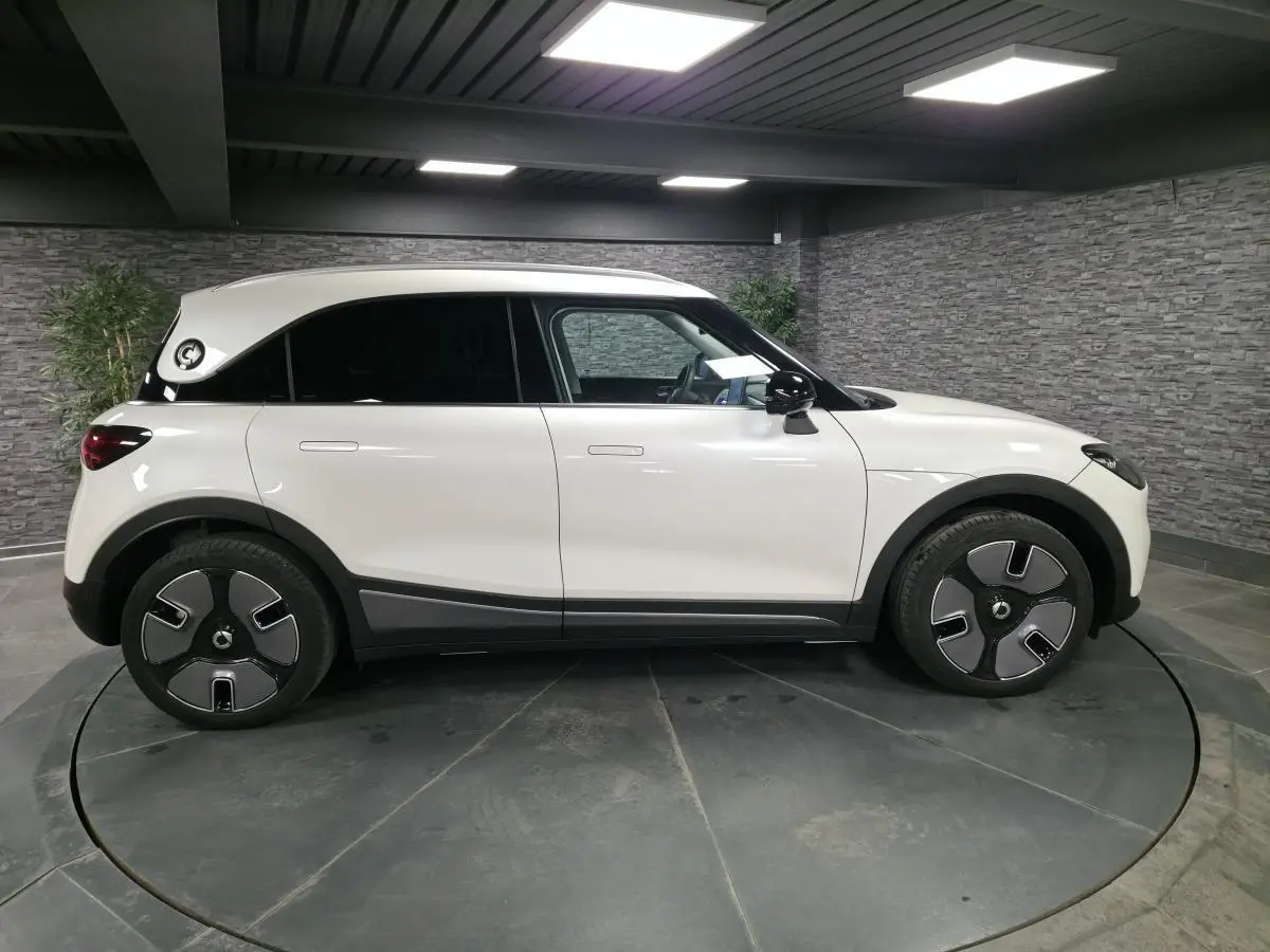 Vue de profil côté gauche d'une Smart Electric 2024 blanche avec jantes 19 pouces et toit panoramique en verre.