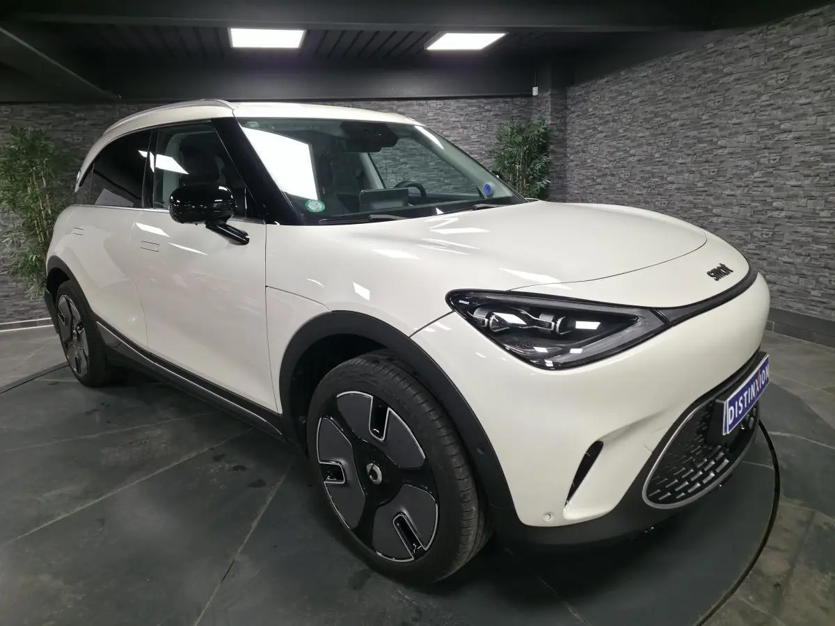 Vue 3/4 avant droit d'une Smart #1 électrique blanche avec jantes noires et toit panoramique en verre.
