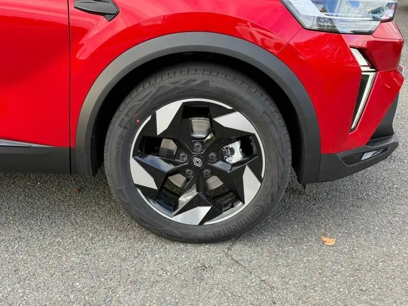 Gros plan sur la roue avant droite du Renault Captur 2025 rouge Flamme avec jante noire et argent au design étoilé.