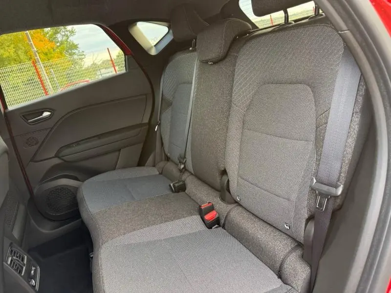 Vue intérieure côté gauche des sièges arrière gris du Renault Captur 2025 Rouge Flamme, avec ceinture de sécurité visible.