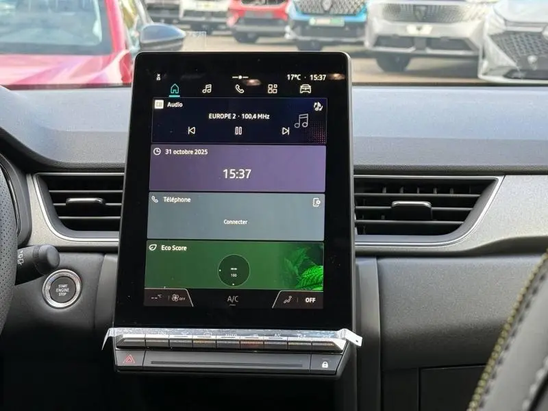 Vue intérieure centrée sur l’écran tactile du tableau de bord du Renault Captur 2025, avec commandes et bouton start/stop visibles.